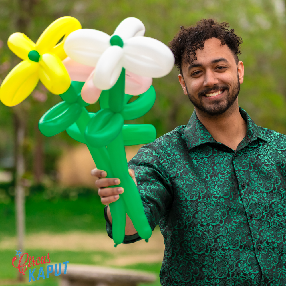 Young man hold out colorful balloon flower creations in Tower Grove Park
